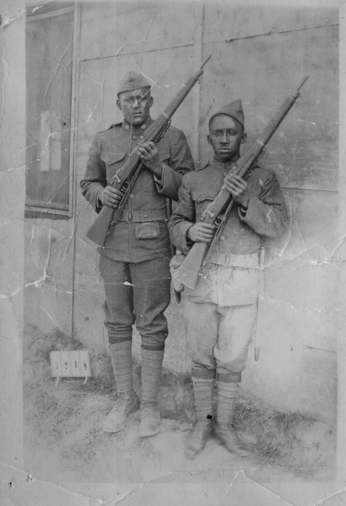 Photograph on postcard of two unidentified soldiers in standard uniform holding rifles
