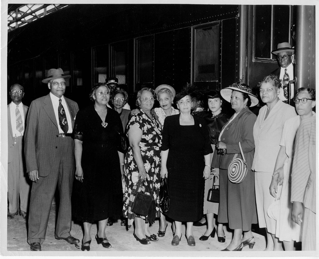 Group photograph  of church members standing beside a train